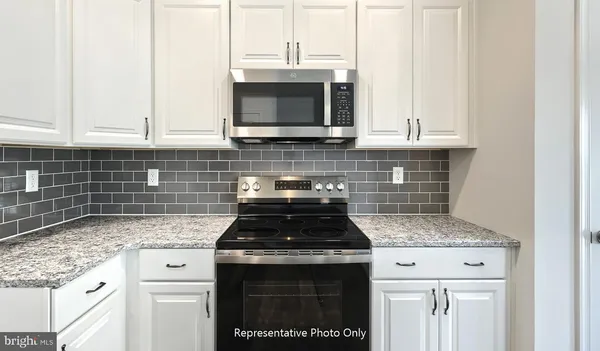 a kitchen with granite countertop a stove sink and microwave