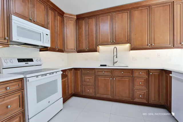 a kitchen with a stove a sink and a refrigerator with wooden floor