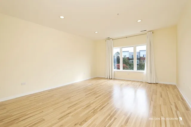 a view of an empty room with wooden floor and a bathroom