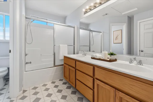a bathroom with a double vanity sink toilet mirror and shower