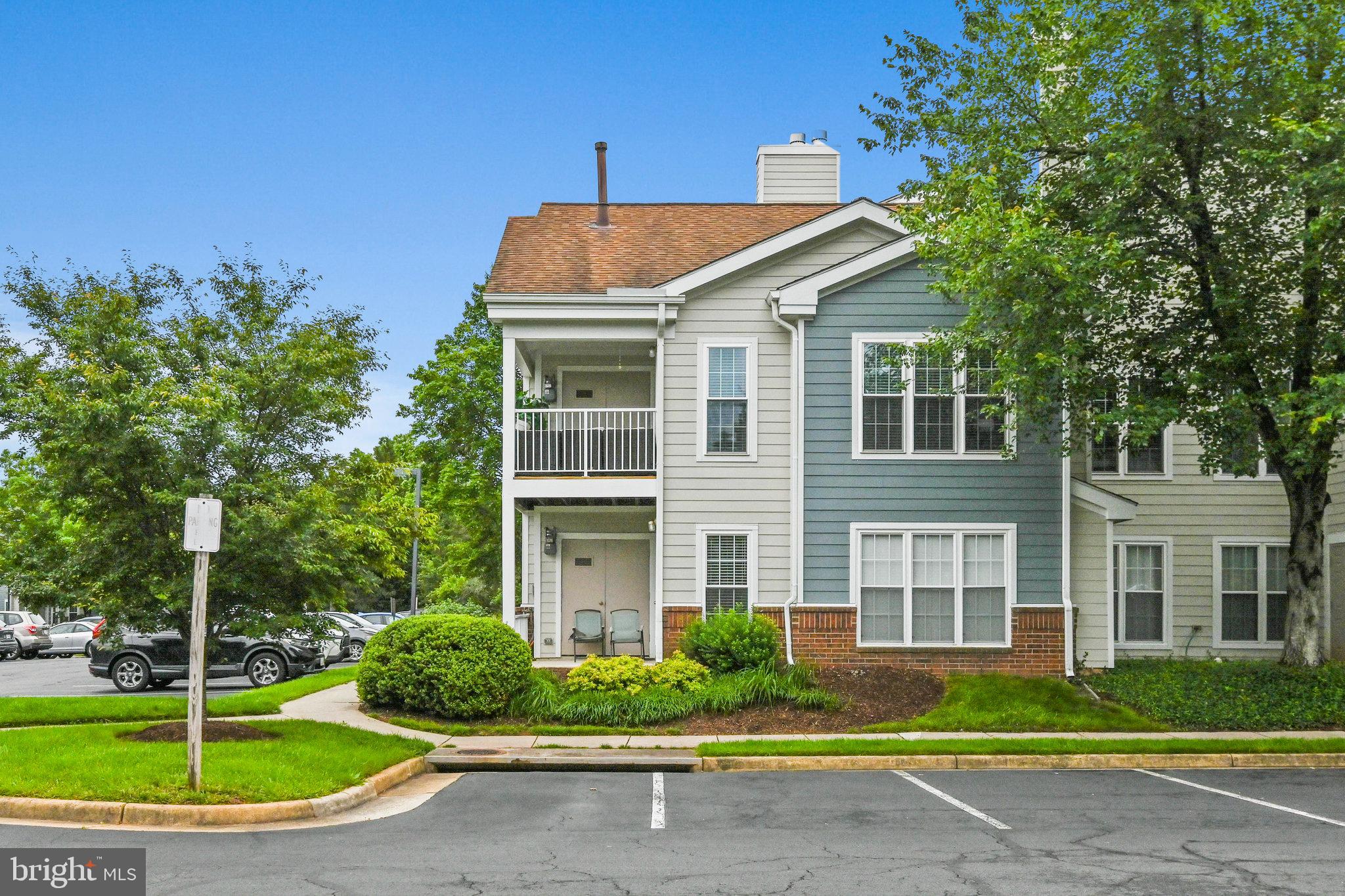 21013 Timber Ridge Terrace, Unit 202 Ashburn, VA 20147 - Photo 1 of 42 a front view of a house with a garden and trees