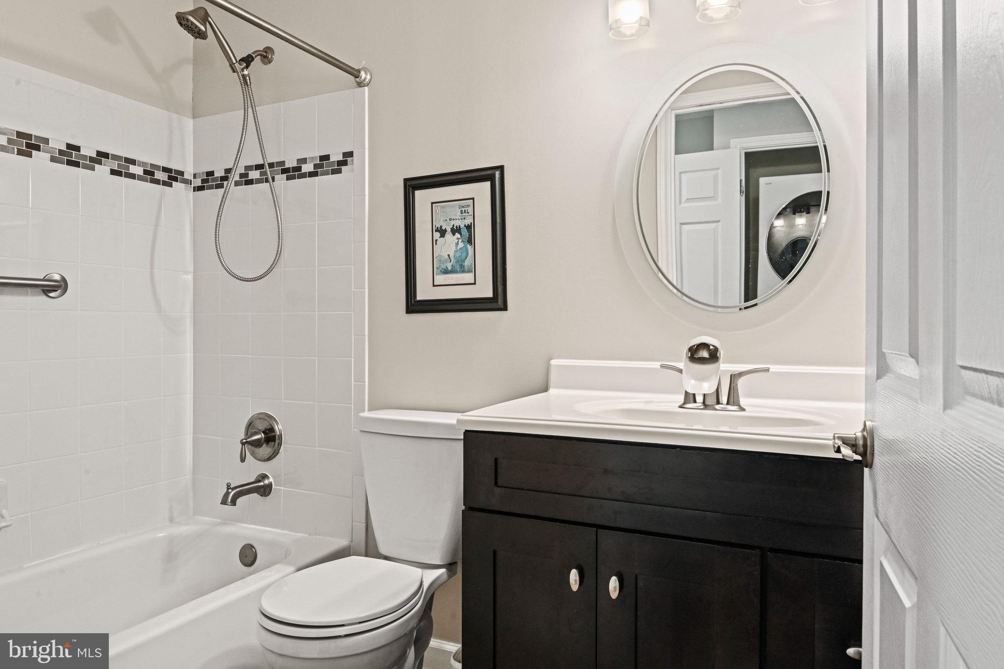 21013 Timber Ridge Terrace, Unit 202 Ashburn, VA 20147 - Photo 15 of 42 a bathroom with a toilet a sink a mirror a vanity and shower