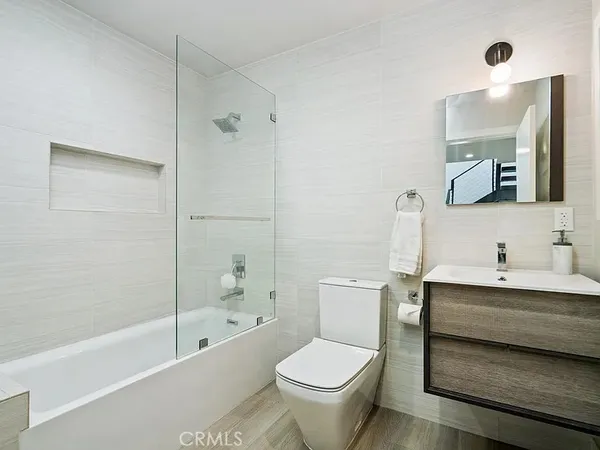a bathroom with a bathtub shower sink mirror and toilet