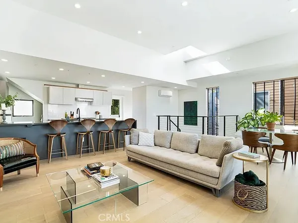 a living room with furniture a rug kitchen view and a table