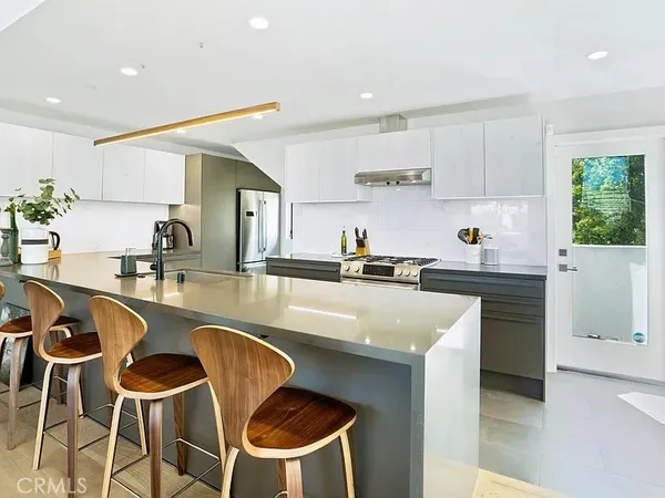 a kitchen with stainless steel appliances granite countertop a table and chairs in it