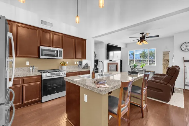 a kitchen with kitchen island granite countertop a stove a sink a microwave a refrigerator and chairs