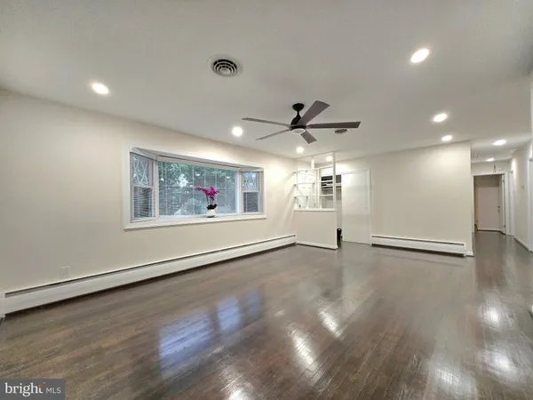 a view of an empty room with a window and wooden floor