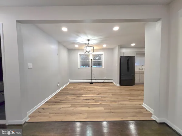an empty room with wooden floor a ceiling fan and windows