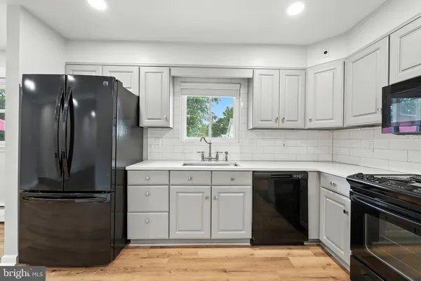 an empty room with wooden floor and kitchen view
