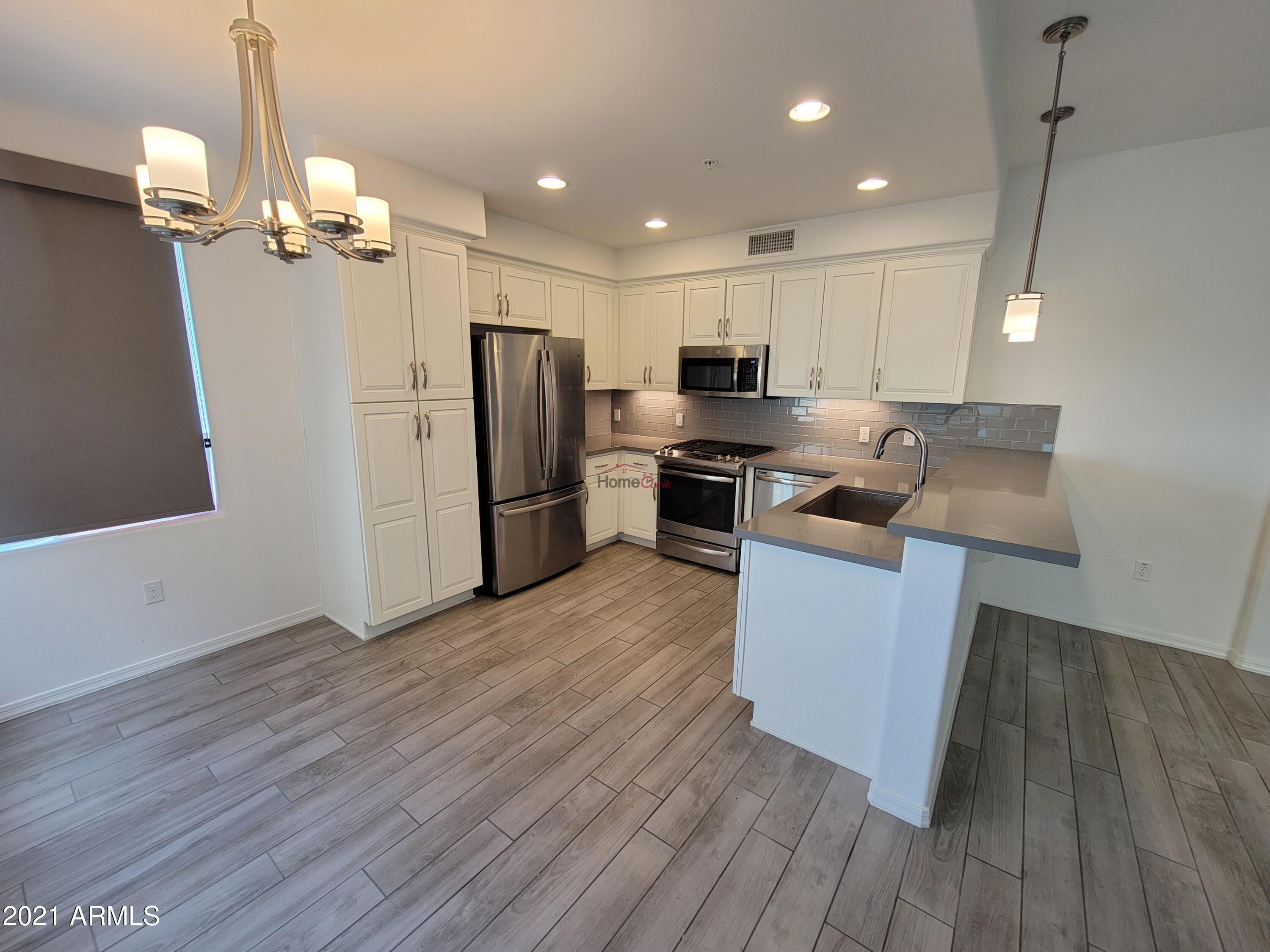 17850 North 68th Street, Unit 2063 Phoenix, AZ 85054 - Photo 18 of 23 a kitchen with stainless steel appliances granite countertop a refrigerator a sink dishwasher a stove and a wooden floor