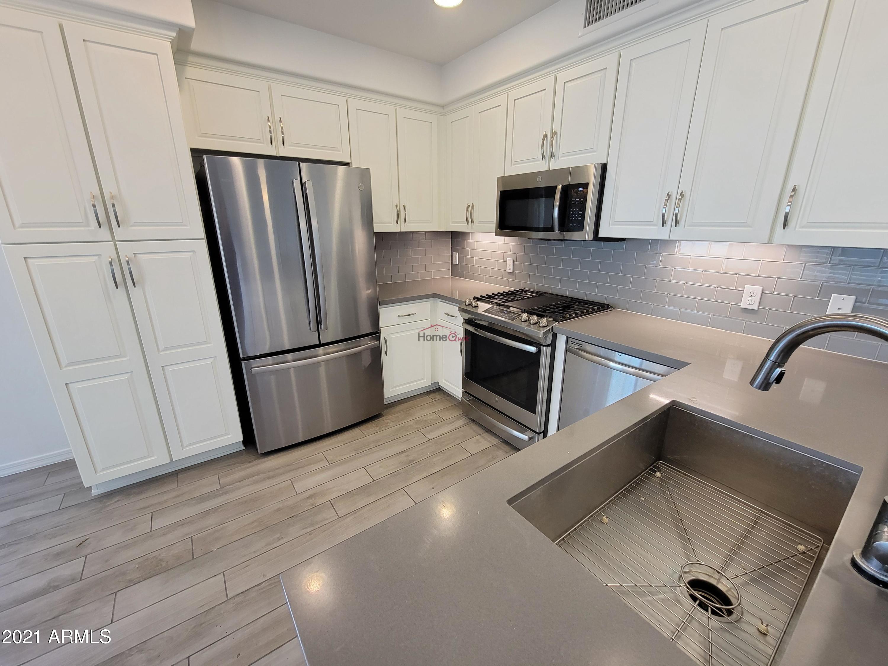 17850 North 68th Street, Unit 2063 Phoenix, AZ 85054 - Photo 20 of 23 a kitchen with granite countertop a refrigerator and a stove top oven