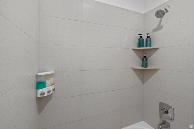 1122 South 1790th West, Unit 1 St. George, UT 84770 - Photo 24 of 37 Shower enclosure featuring light-toned tile walls, a chrome shower head, and dual built-in corner shelves
