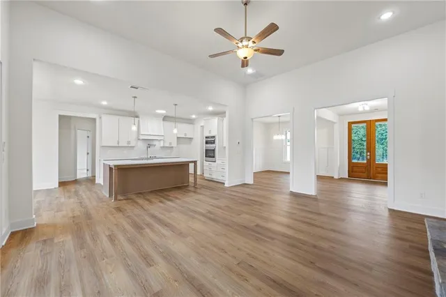a view of an empty room and kitchen with wooden floor