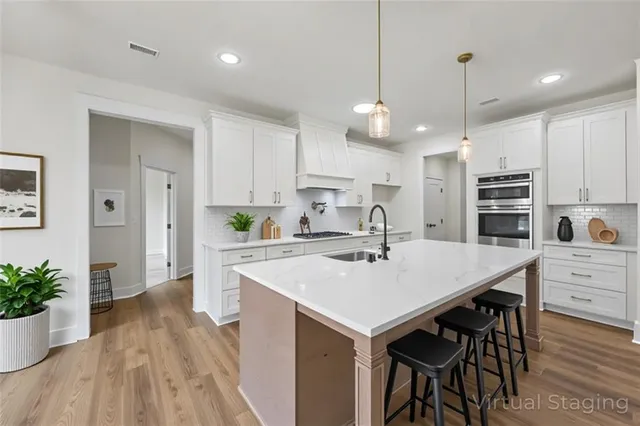 a large kitchen with kitchen island a stove a sink a refrigerator and a dining table with wooden floor