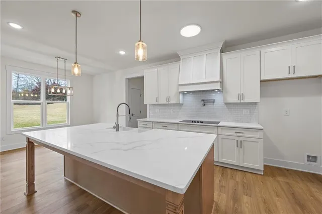 a kitchen with stainless steel appliances granite countertop a sink a stove a refrigerator and white cabinets with wooden floor