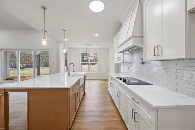 a open kitchen with kitchen island a sink stove and wooden floor