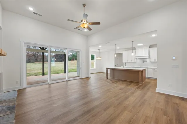 a view of an empty room with wooden floor and a kitchen