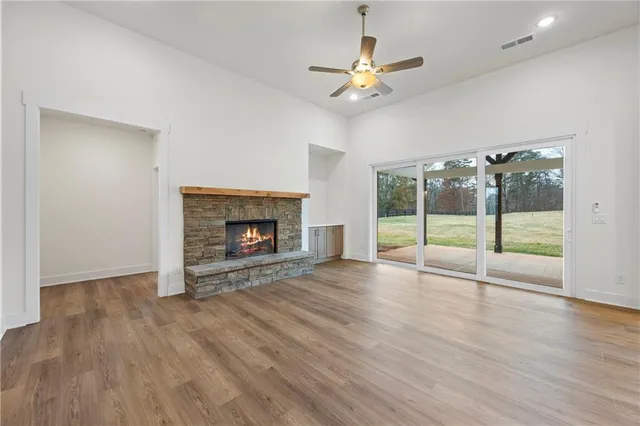 a view of an empty room with wooden floor fireplace and a window