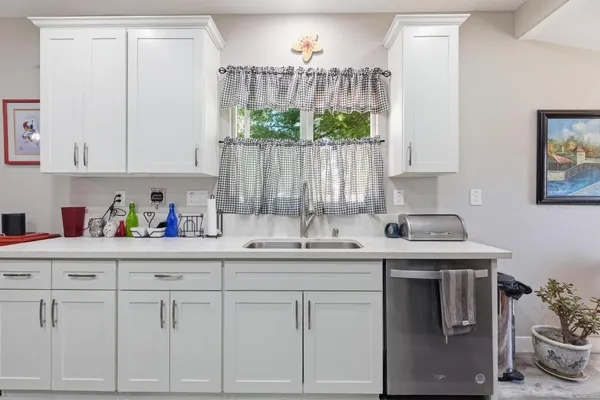 a kitchen with white cabinets and sink