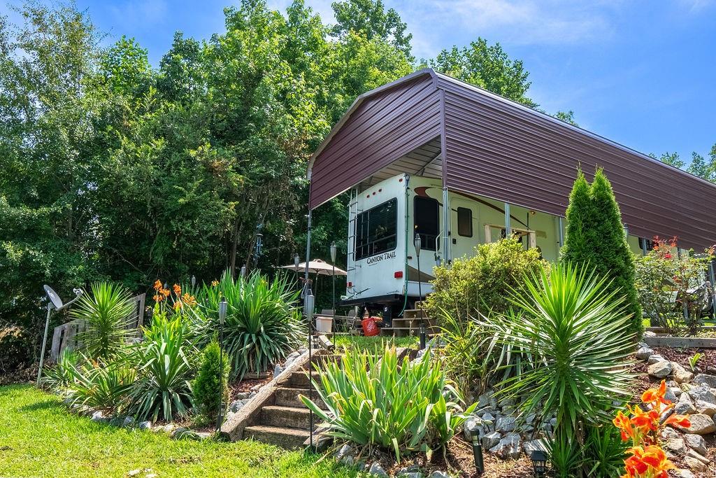 208 Reston Way Westminster, SC 29693 - Photo 25 of 32 This lush landscape features a convenient carport, ideal for recreation vehicles, with verdant surroundings.