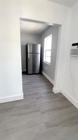 a view of empty room with wooden floor and kitchen