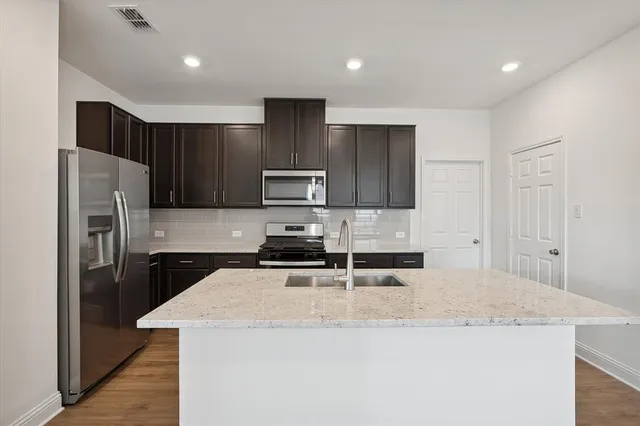a kitchen with kitchen island a sink stainless steel appliances and cabinets
