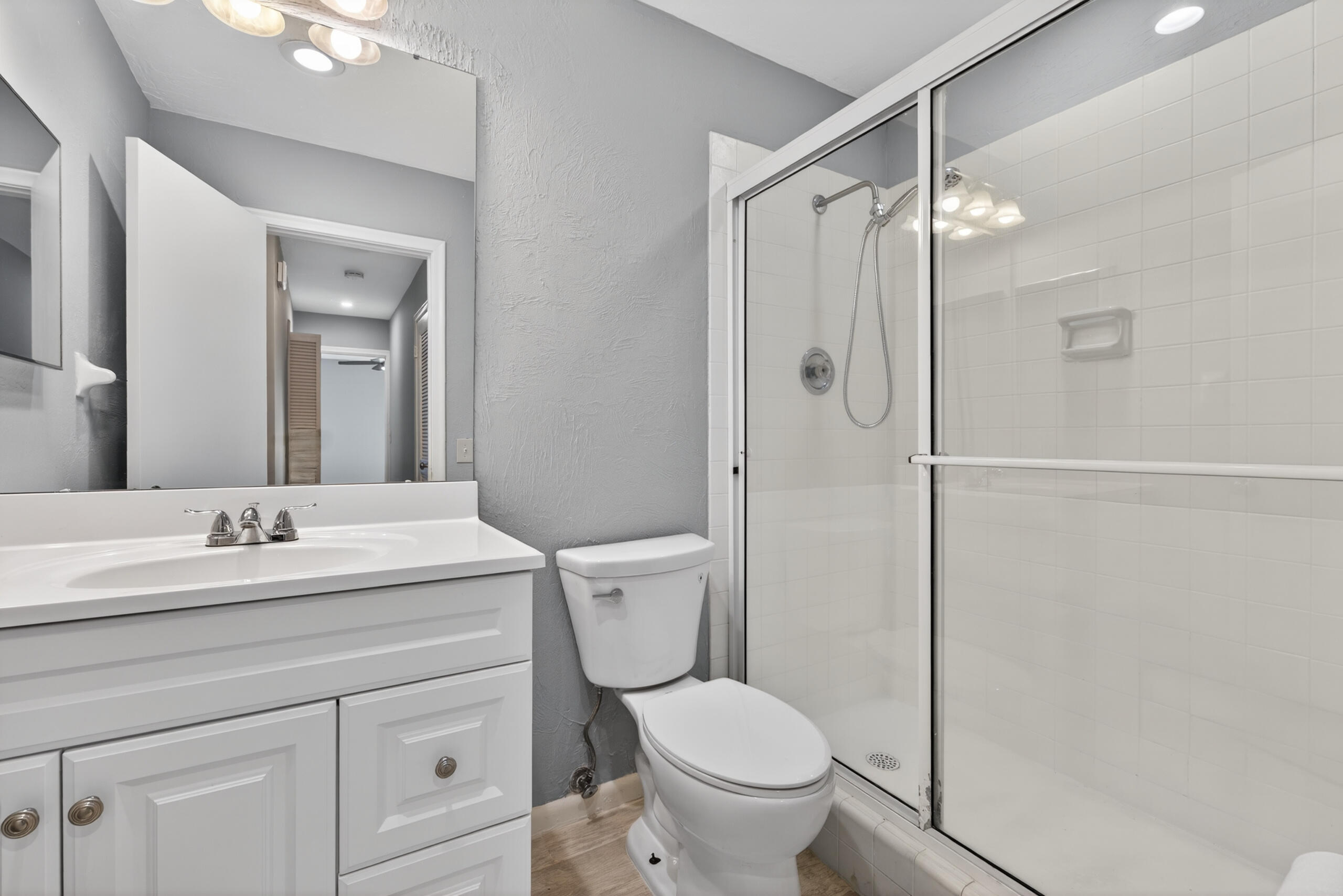 423 Pine Tree Court, Unit 23 Atlantis, FL 33462 - Photo 11 of 33 a bathroom with a granite countertop sink toilet a mirror a vanity and shower