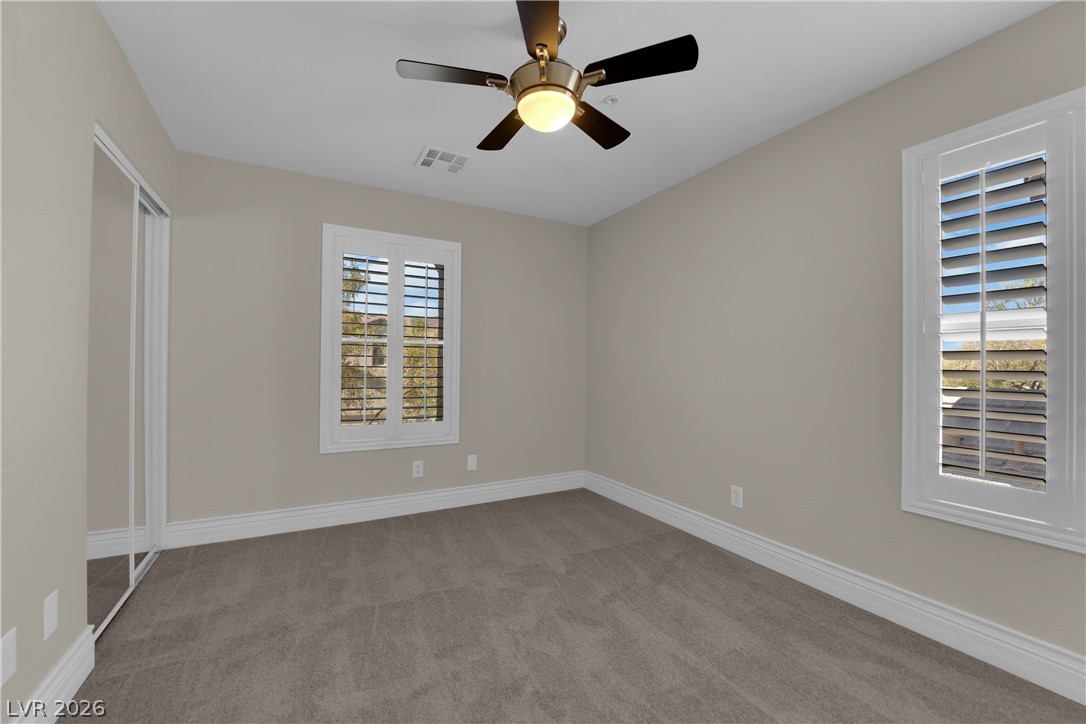 646 Monument Point Street Henderson, NV 89002 - Photo 17 of 44 A well-lit bedroom features plush carpeting and two windows with elegant plantation shutters.