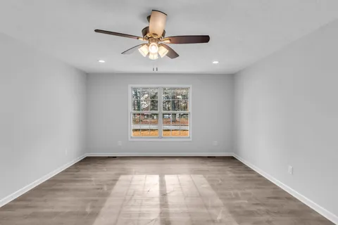 en empty room with windows and chandelier fan