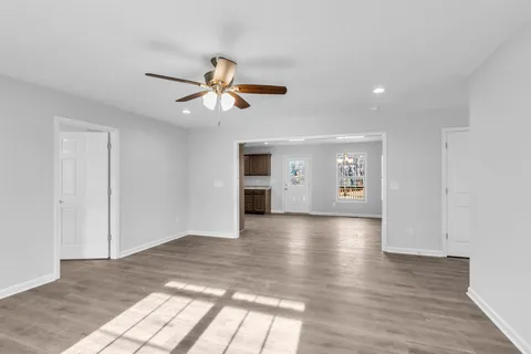 a view of an empty room with window and wooden floor