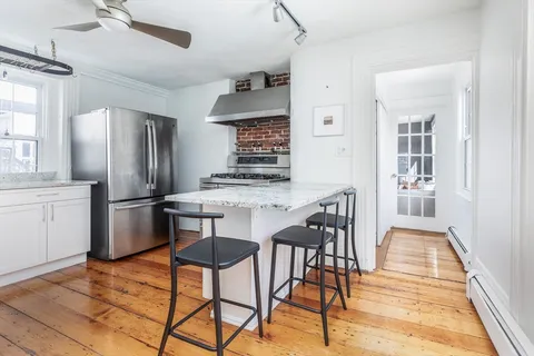 a kitchen with stainless steel appliances granite countertop a dining table chairs refrigerator and sink