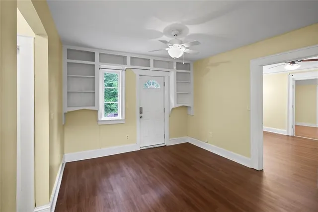 an empty room with wooden floor chandelier and windows
