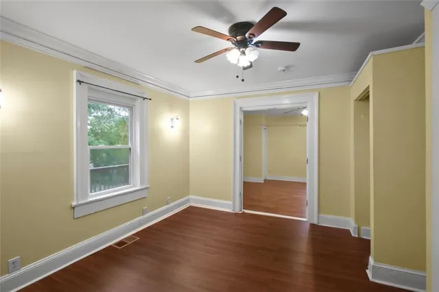 a view of an empty room with a window and wooden floor