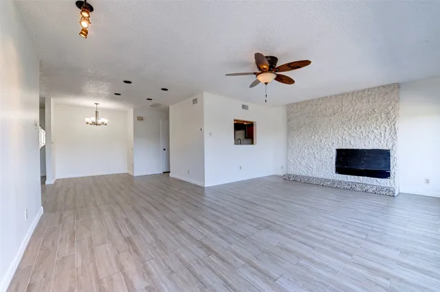 an empty room with wooden floor ceiling fan and windows