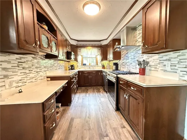 a kitchen with stainless steel appliances granite countertop wooden cabinets and a wooden floor