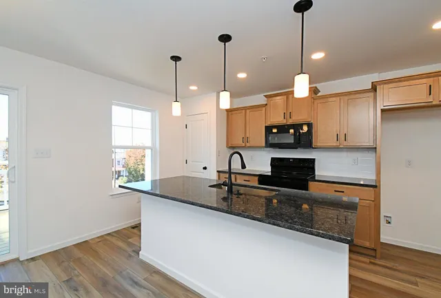 a kitchen with granite countertop kitchen island stainless steel appliances sink and wooden floor