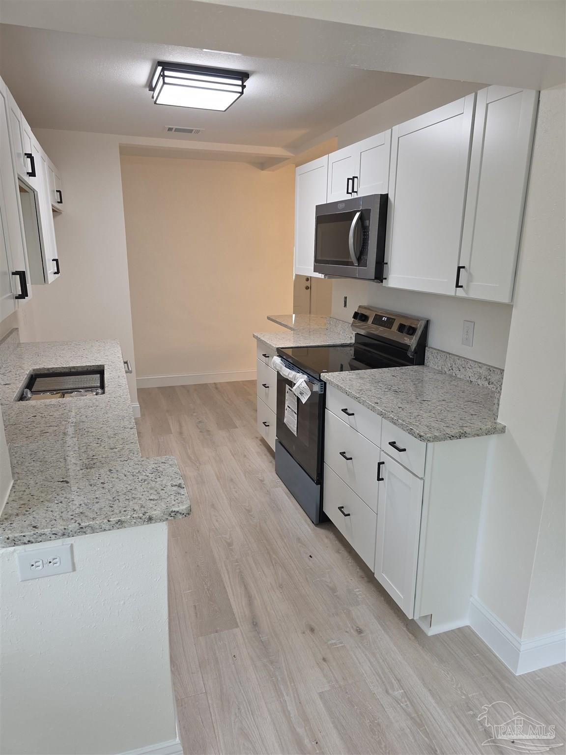 302 Dixie Street Crestview, FL 32536 - Photo 11 of 17 a kitchen with stainless steel appliances granite countertop a sink microwave and stove