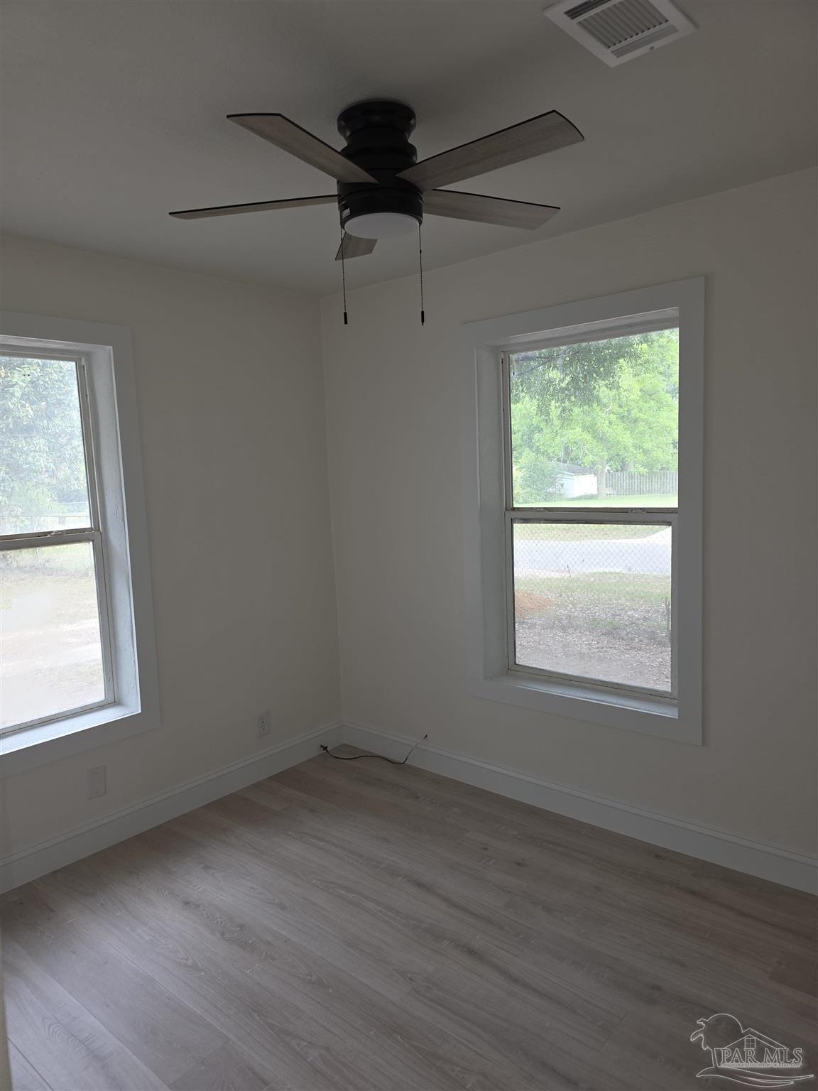 302 Dixie Street Crestview, FL 32536 - Photo 16 of 17 an empty room with wooden floor and windows