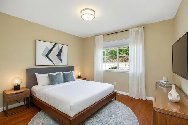 a bedroom with a bed and a flat tv screen on a dresser