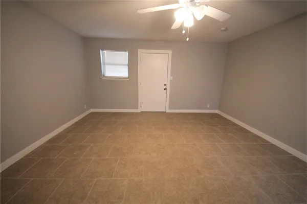 an empty room with a chandelier fan and windows