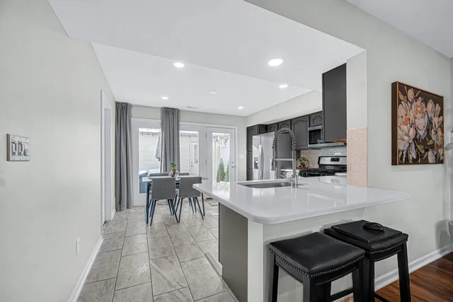 a view of a kitchen with kitchen island a dining table chairs and a refrigerator