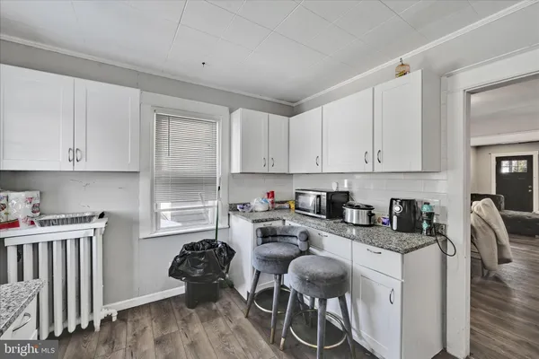 a kitchen with stainless steel appliances granite countertop a stove top oven a sink dishwasher and white cabinets with wooden floor