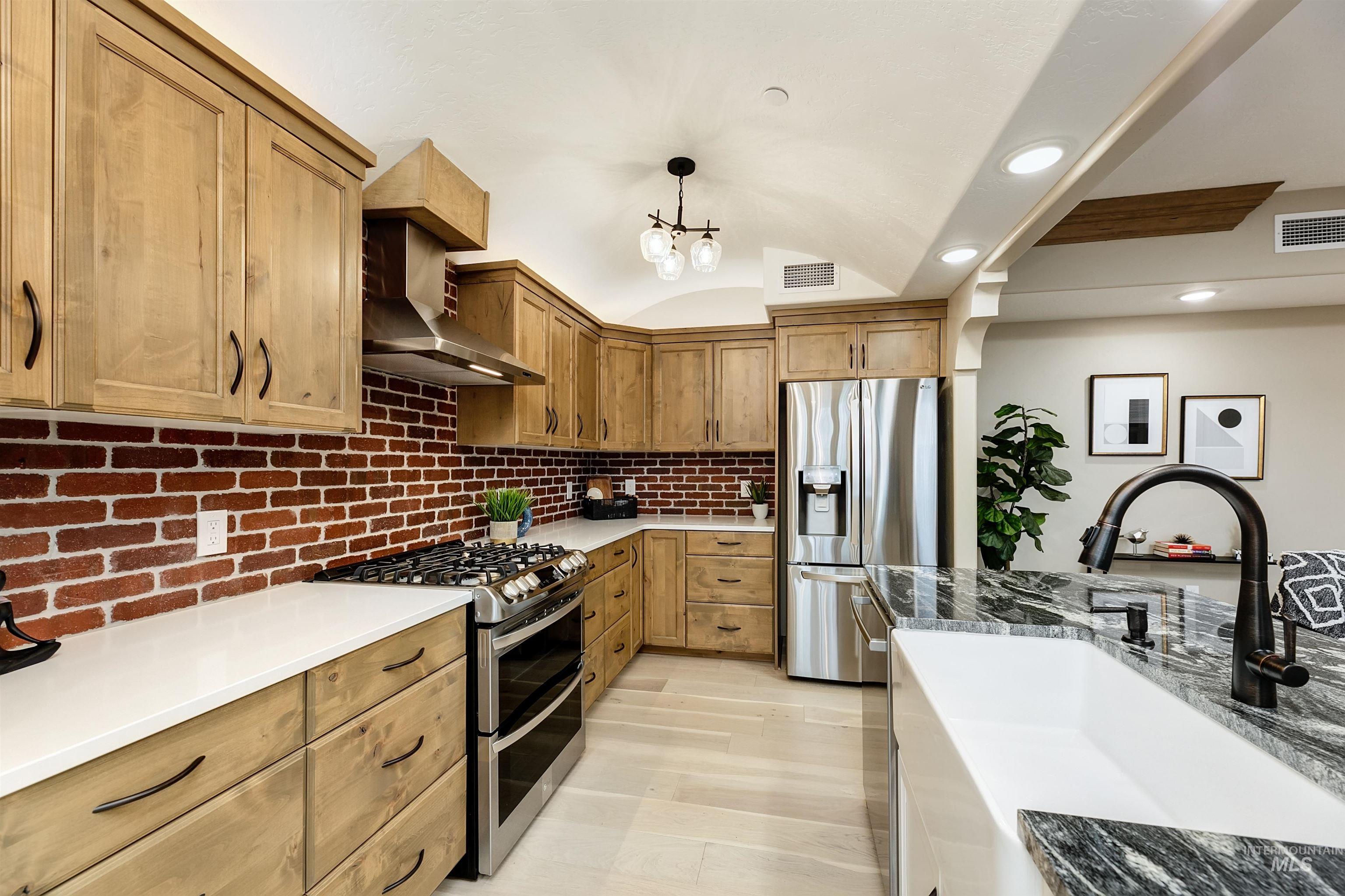 79 West Aikens Road, Unit 203 Eagle, ID 83616 - Photo 16 of 41 Kitchen with stainless steel appliances, light stone counters, a barrel ceiling, hanging light fixtures, and wood finish cabinetry