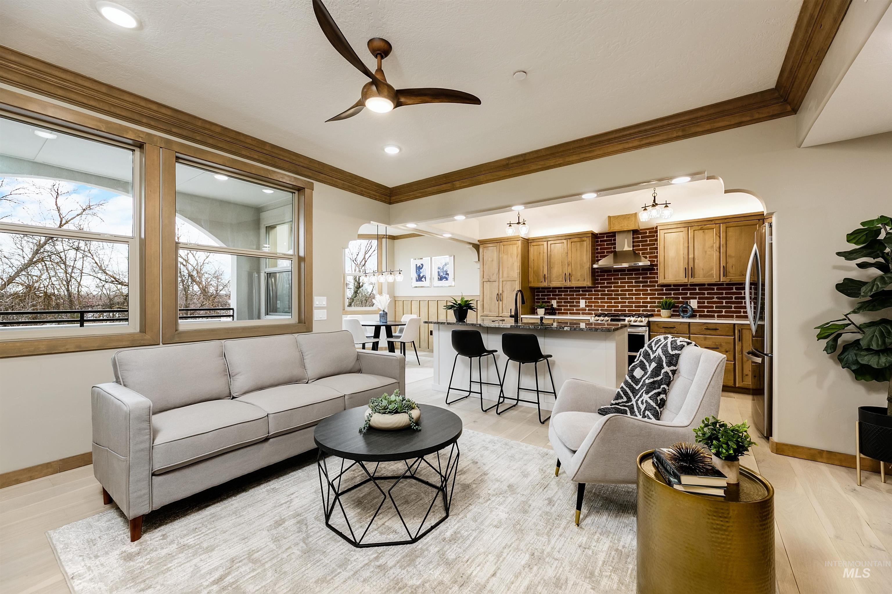 79 West Aikens Road, Unit 203 Eagle, ID 83616 - Photo 4 of 41 Living area with arched walkways, ceiling fan, light wood finished floors, and crown molding