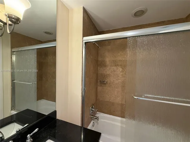 a bathroom with a sink and mirror with bathtub