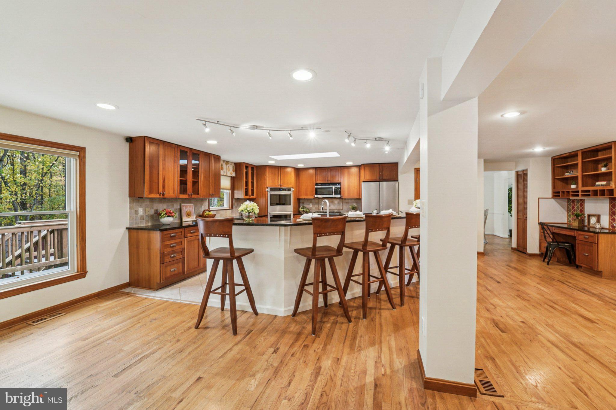 14820 Windmill Terrace Silver Spring, MD 20905 - Photo 11 of 33 a open kitchen with stainless steel appliances granite countertop a refrigerator a stove top oven a dining table and chairs with wooden floor