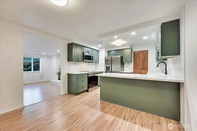 a kitchen with stainless steel appliances granite countertop a sink a stove top oven and wooden floor