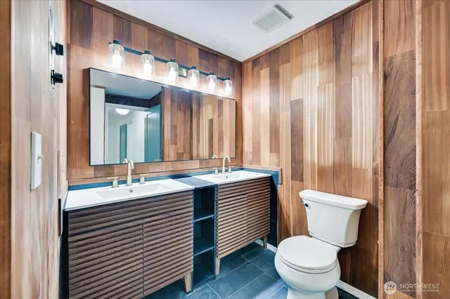 a bathroom with a double vanity sink toilet and a mirror