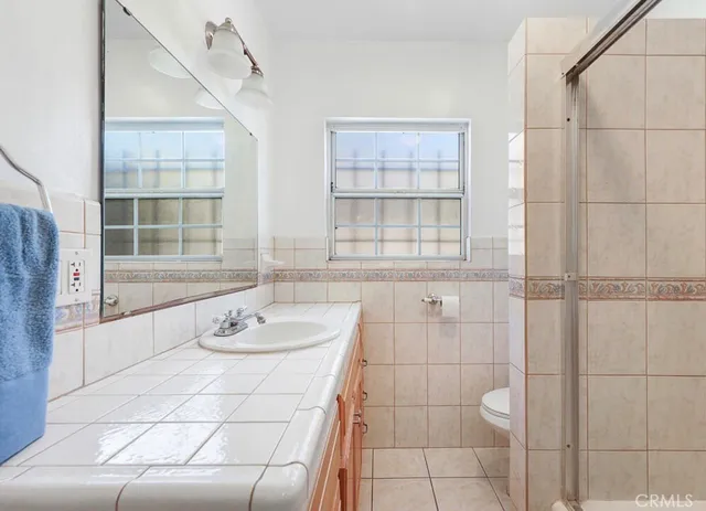 a bathroom with a granite countertop sink a toilet and shower