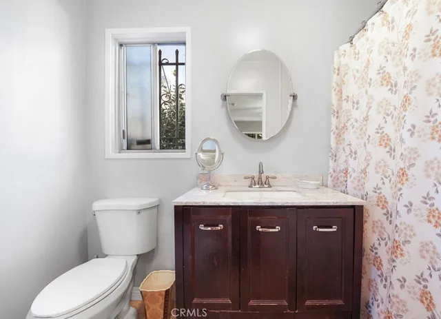a bathroom with a granite countertop toilet a sink and a mirror